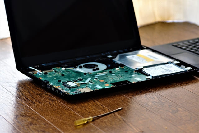 分解されたノートパソコンとドライバーを写した写真で、修理の作業を表している