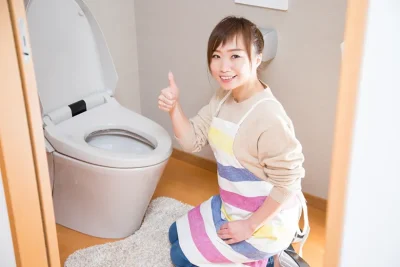 トイレでナイスのハンドサインをする笑顔の女性