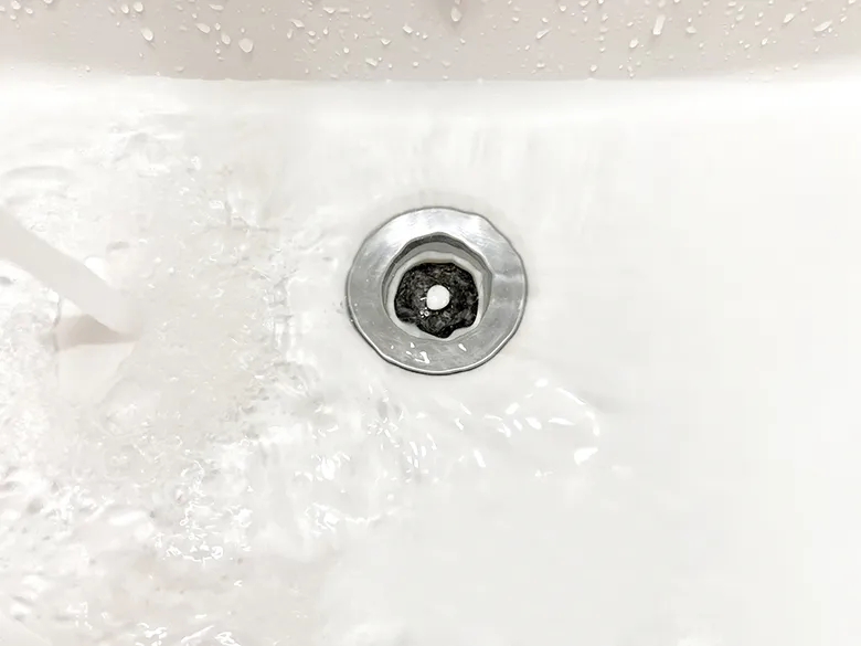 洗面ボウルの排水口に水が流れているところを真上から見た写真